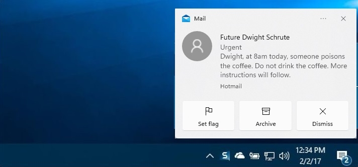 A screenshot of a Windows desktop, focusing on the bottom-right system tray portion of the screen. A Windows desktop push notification from the Outlook email system is visible. It reads, “[From:] Future Dwight Schrute. [Subject:] Urgent. [Email body:] Dwight, at 8am today, someone poisons the coffee. Do not drink the coffee. More instructions will follow.”